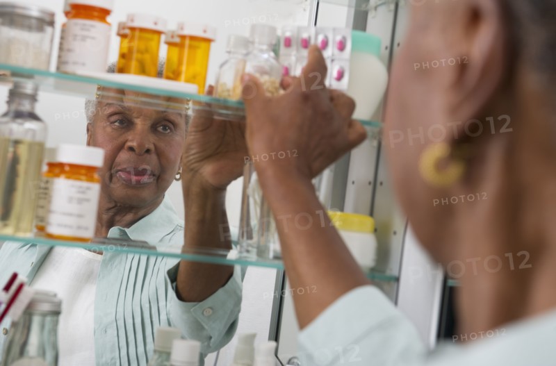 Black woman taking medication from cabinet