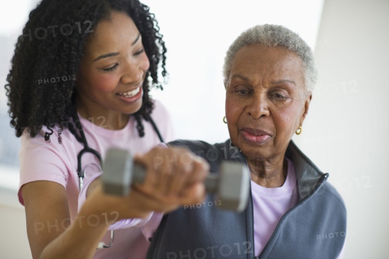 Nurse helping woman exercise with dumbbell