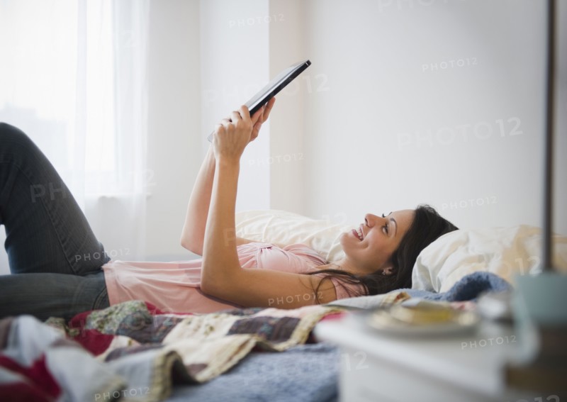 Brazilian woman using digital tablet in bed