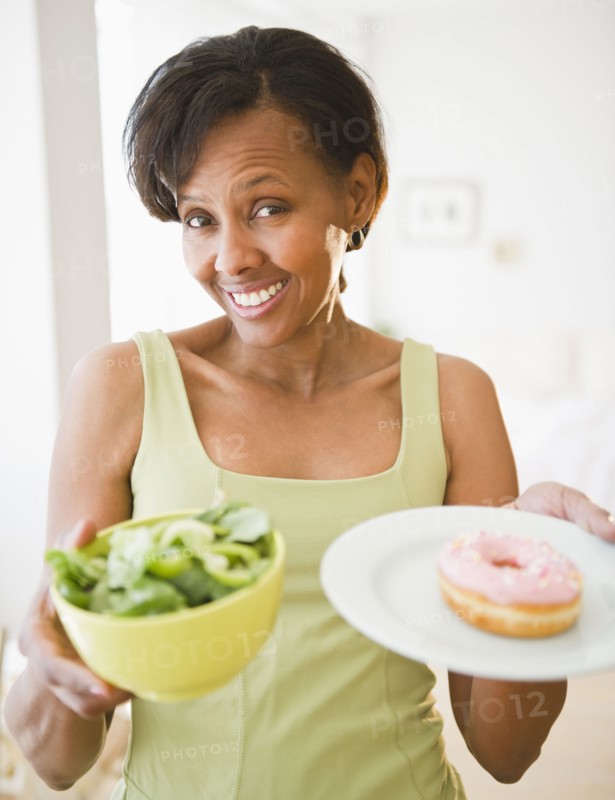Black woman holding salad and donut