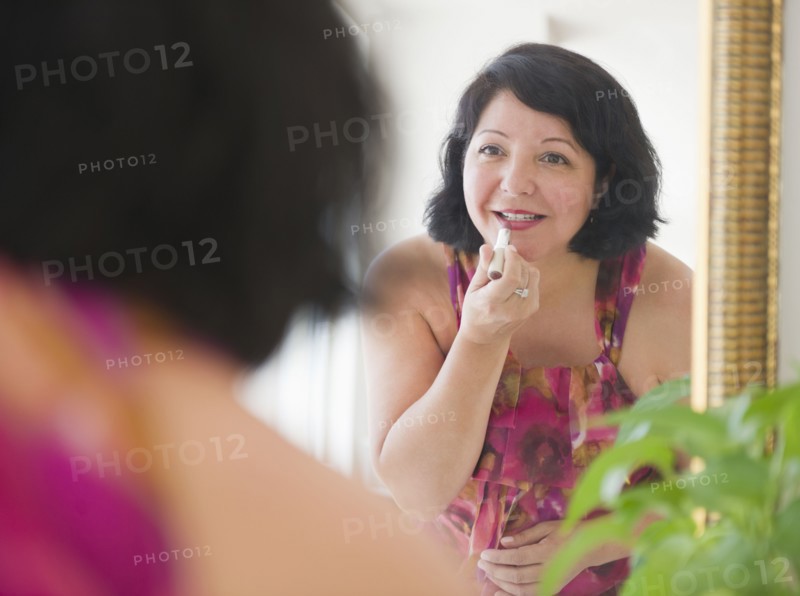 Hispanic woman putting on lipstick