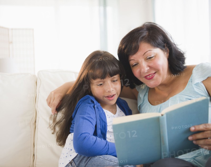 Hispanic mother and daughter reading a book