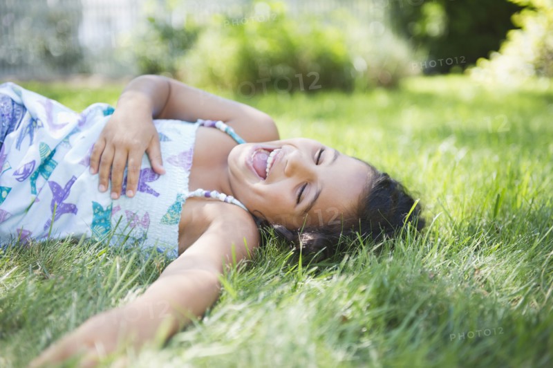 Laughing Hispanic girl laying in grass
