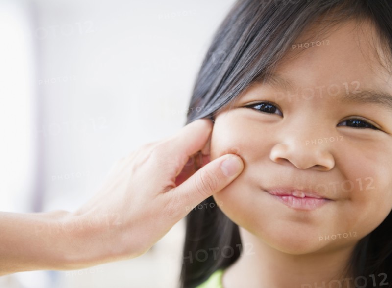 Mother pinching Korean girl's cheek