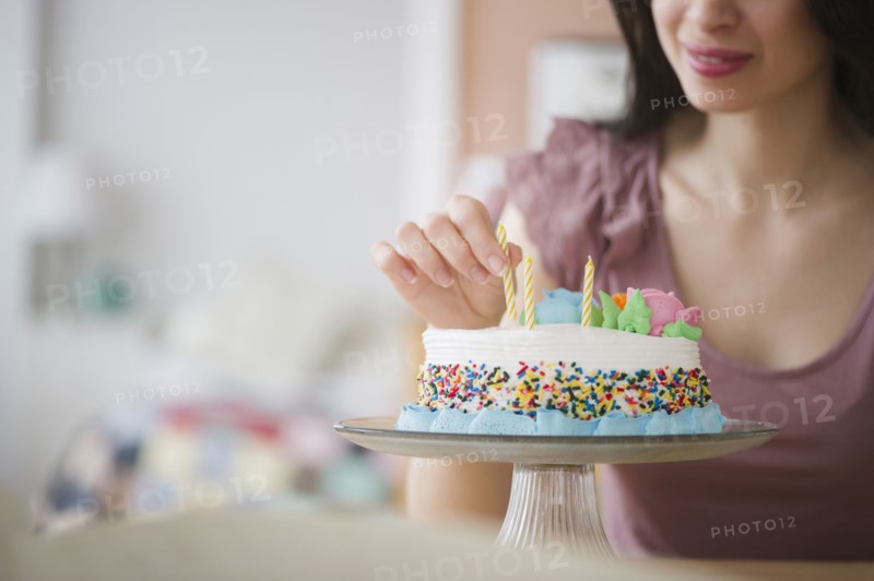 Mixed race woman preparing birthday cake