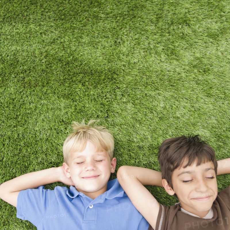 Boys with eyes closed laying in grass