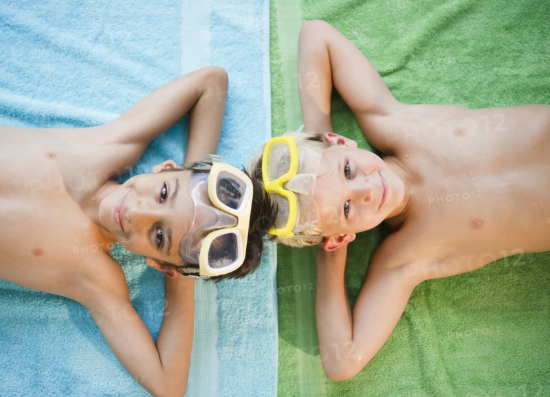Boys laying on towels wearing swim goggles
