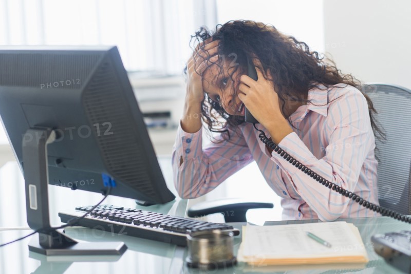 Hispanic businesswoman talking on telephone at desk