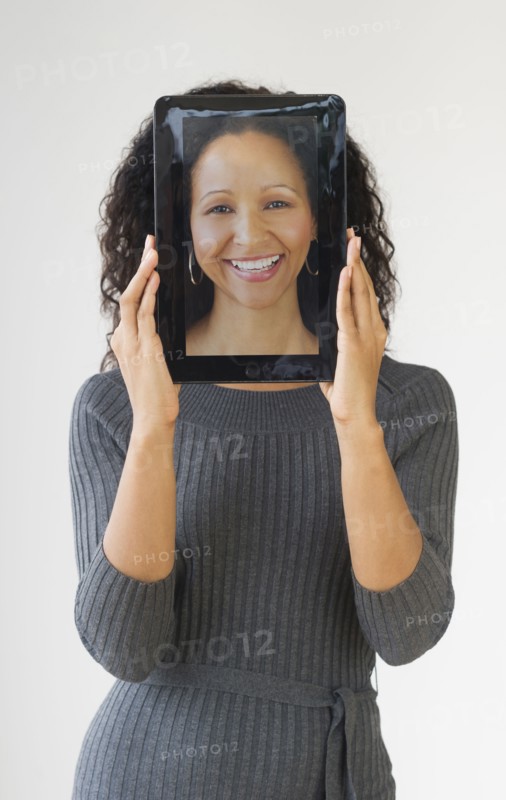 Hispanic woman holding digital tablet in front of face