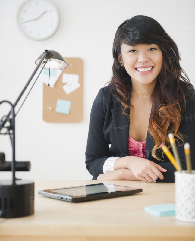 Pacific Islander businesswoman sitting at desk with digital tablet