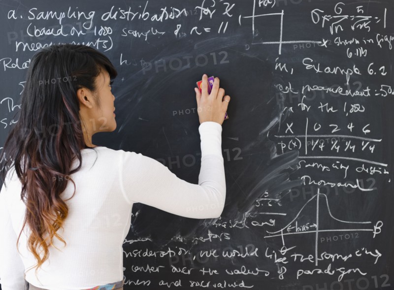 Pacific Islander teacher erasing math from blackboard