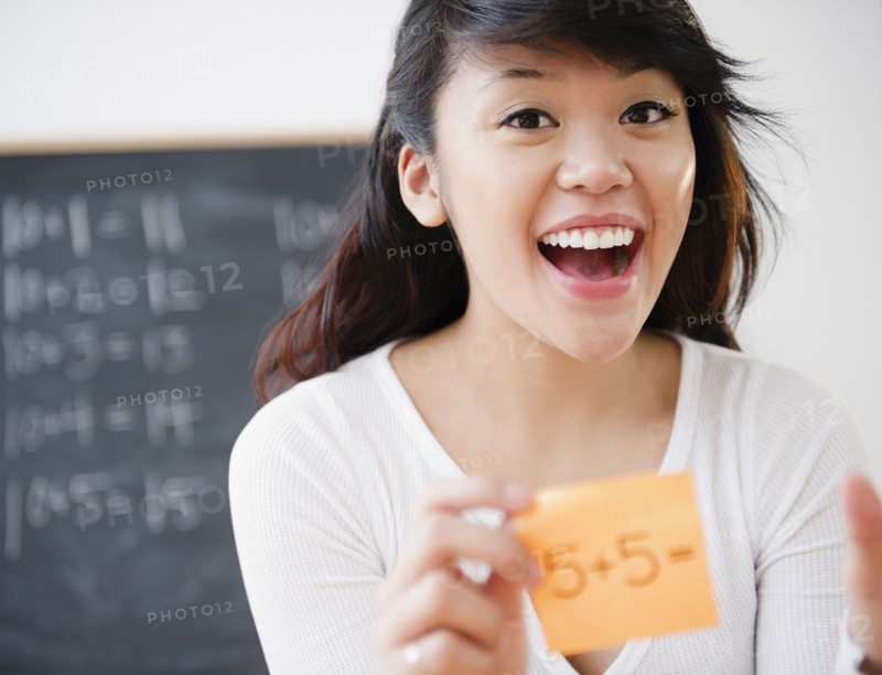 Pacific Islander teacher holding sticky note with math problem