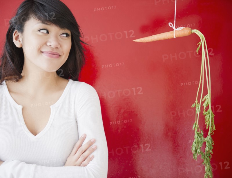 Pacific Islander woman looking at a carrot on a string