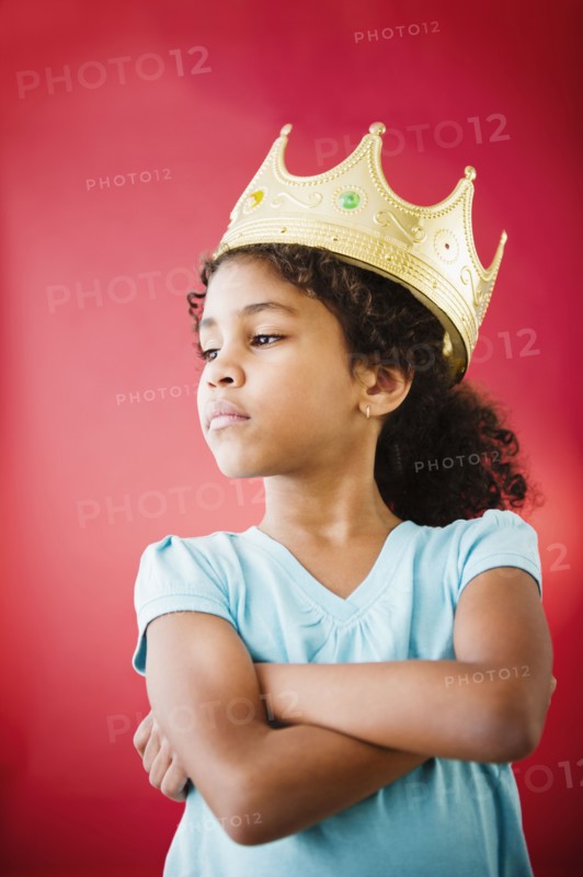 Mixed race girl with arms crossed wearing crown