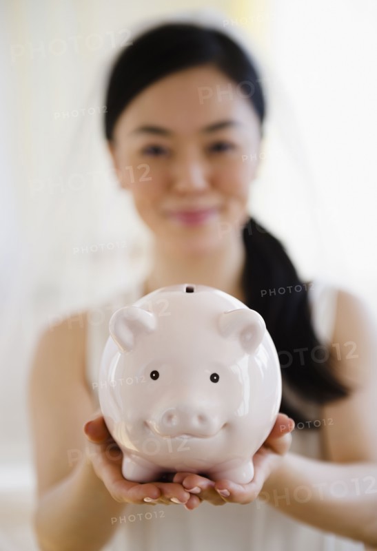 Japanese bride holding piggy bank