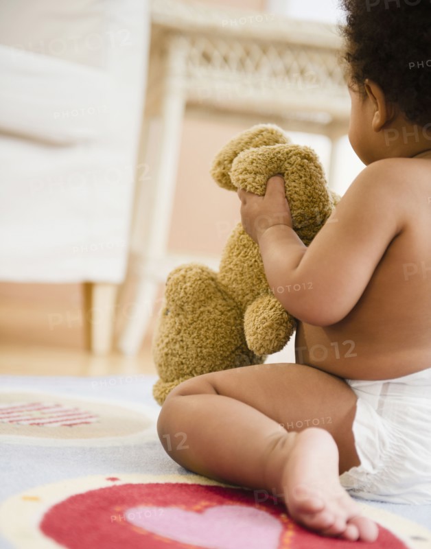 Black baby girl holding teddy bear