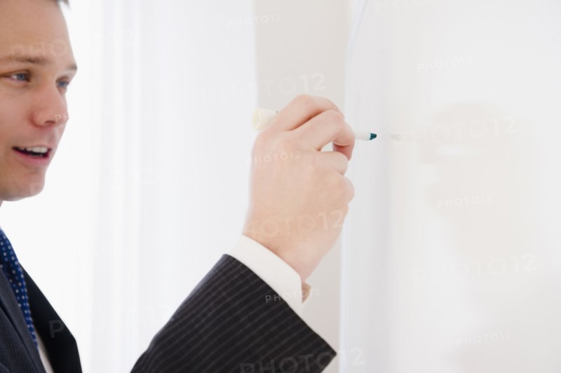 Caucasian businessman writing on whiteboard