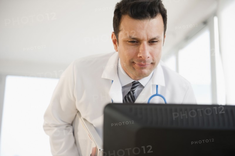 Mixed race doctor looking at computer monitor