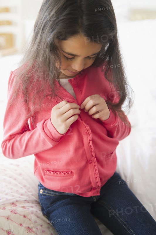Mixed race girl buttoning her shirt