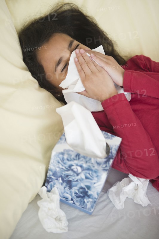 Mixed race girl blowing her nose