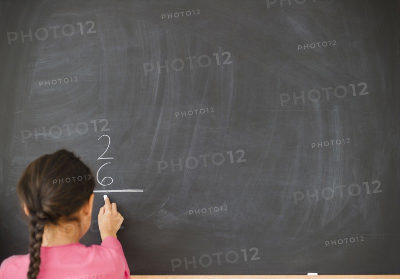 Mixed race girl doing math on blackboard