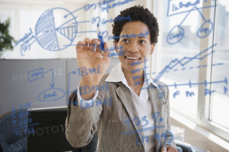 African American businesswoman writing on glass board