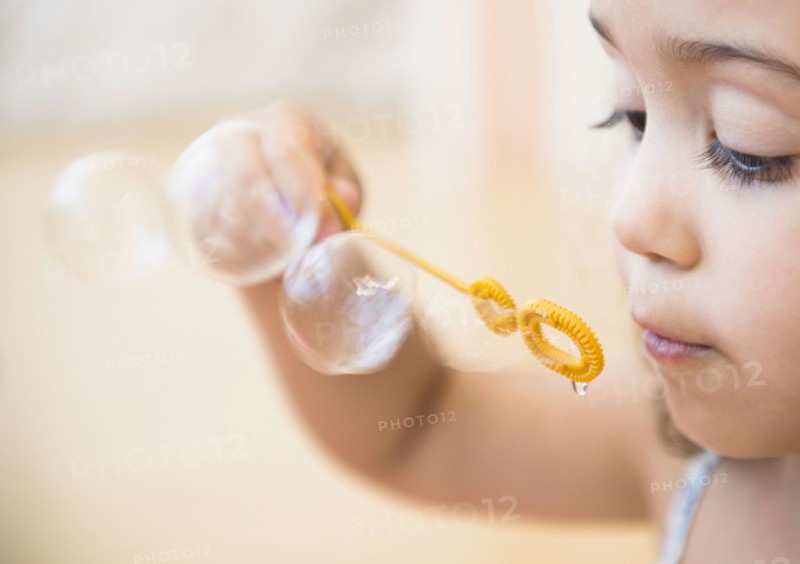 Mixed race girl blowing bubbles