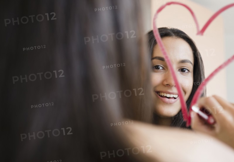 Hispanic teenager drawing heart with lipstick