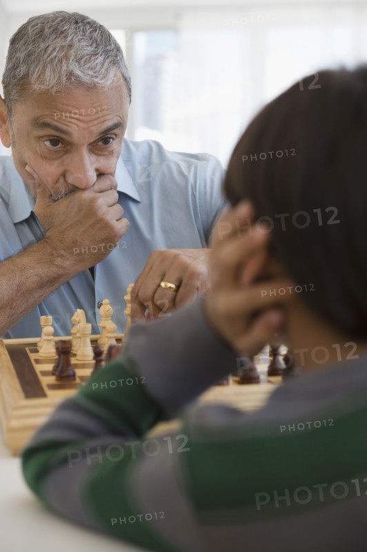 Hispanic grandfather and grandson playing chess