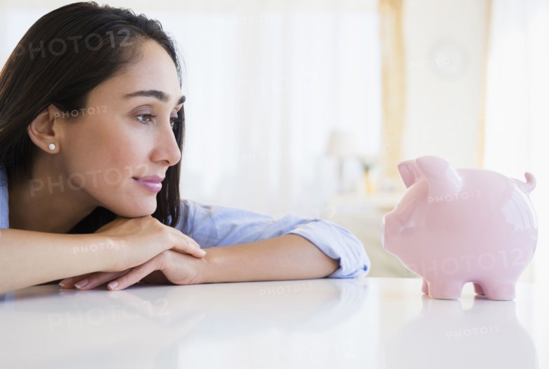 Caucasian businesswoman examining piggy bank