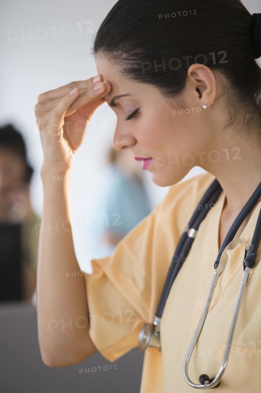 Nurse rubbing her forehead in hospital