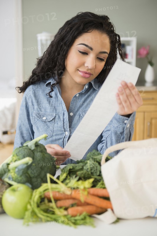 Hispanic woman reading grocery receipt