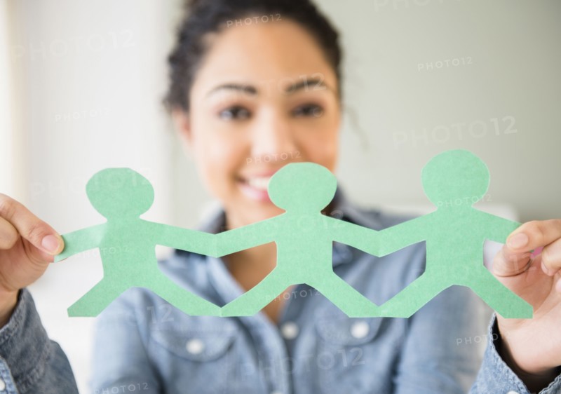 Hispanic woman holding paper dolls