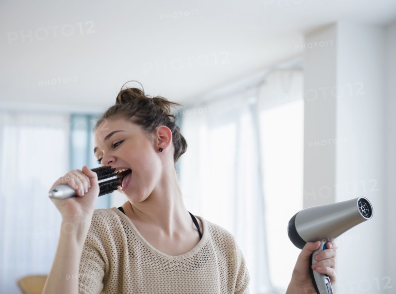 Hispanic girl singing into hairbrush