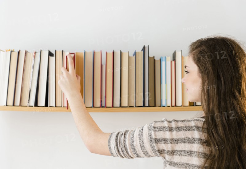 Hispanic girl selecting book from shelf