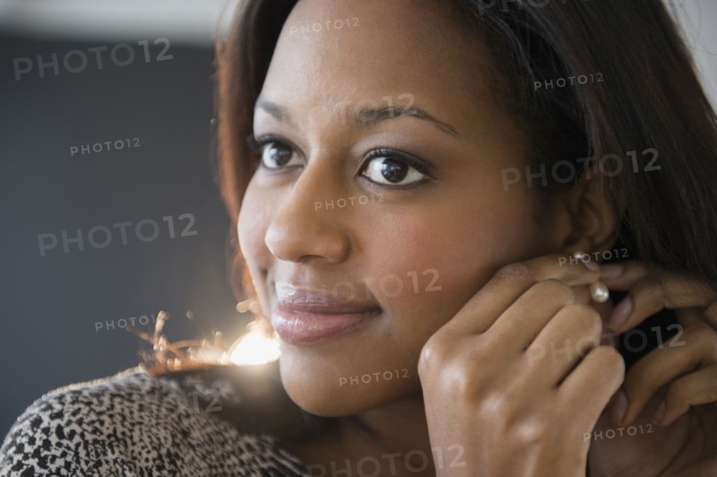 African American woman putting on earrings