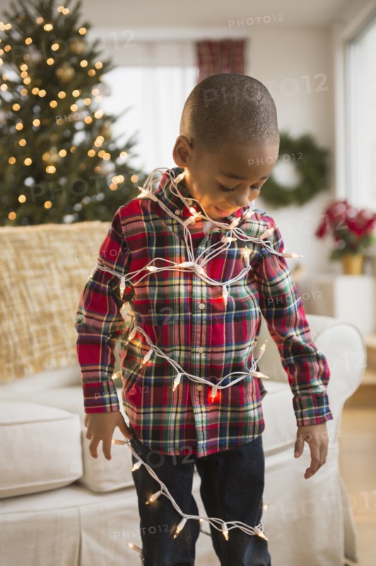African American boy wrapped in Christmas lights