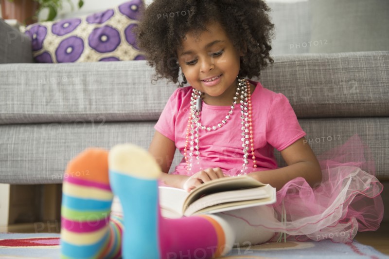 African American girl reading in living room