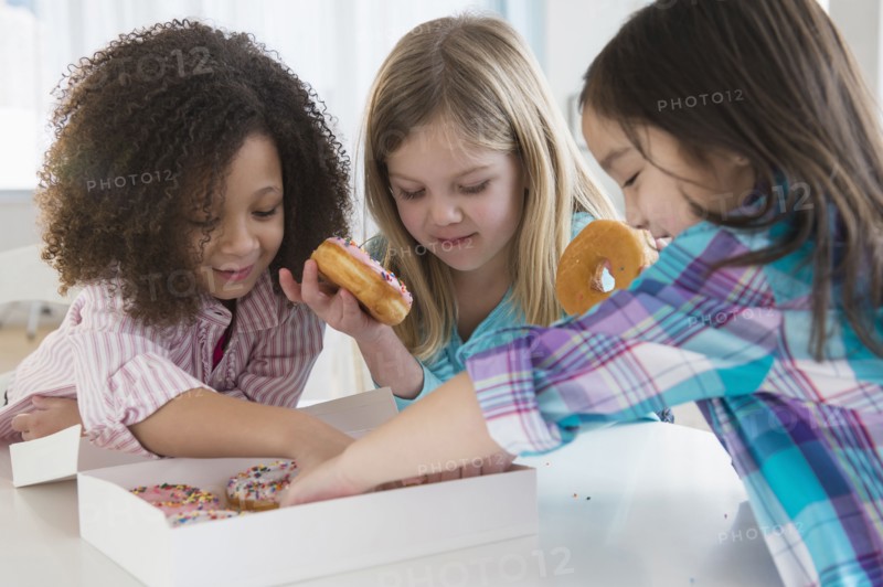 Girls eating donuts together in kitchen