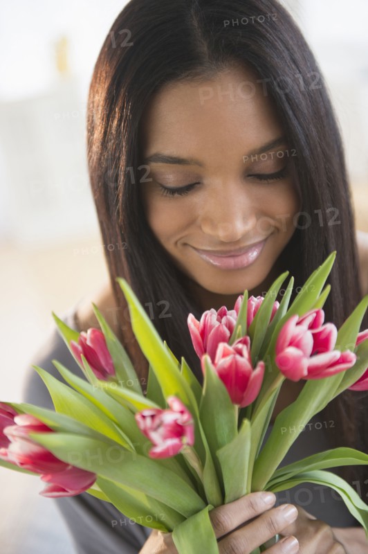Mixed race woman smelling flowers