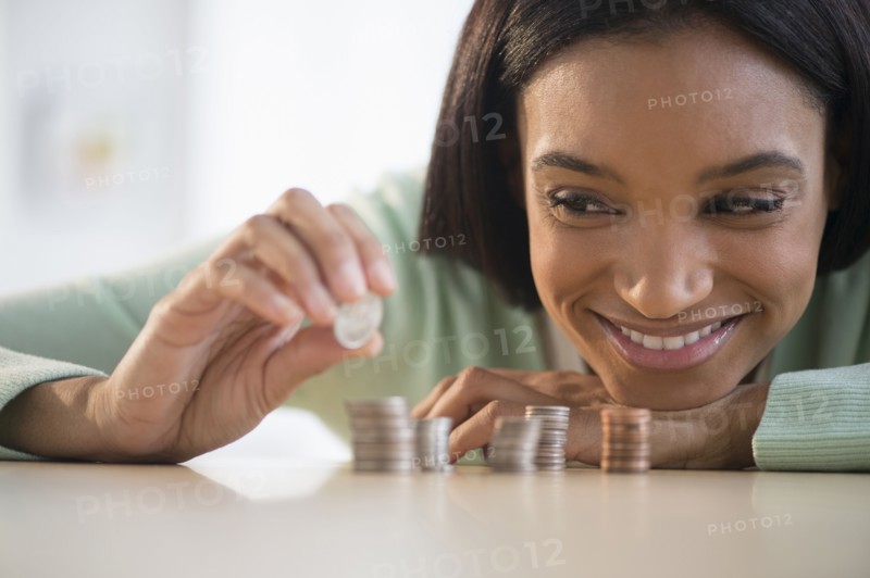Mixed race woman stacking coins