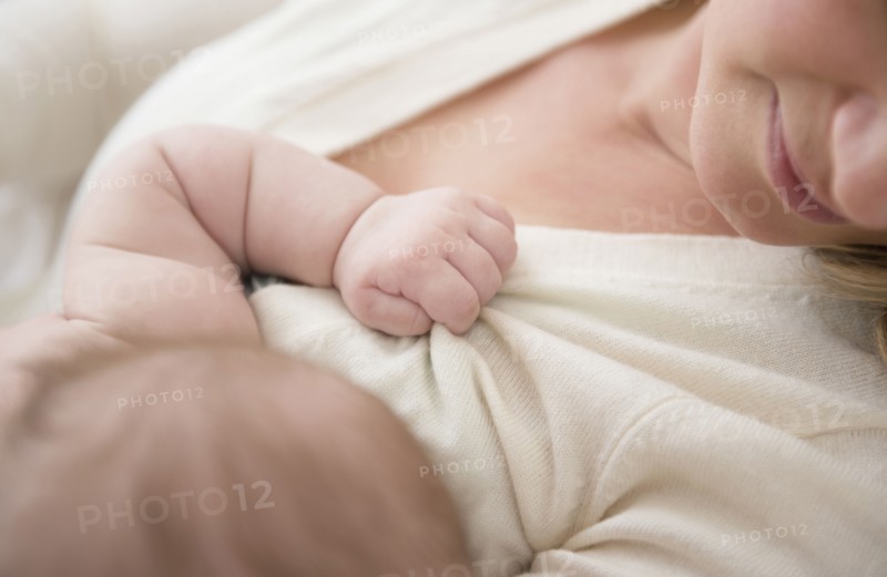 Caucasian baby gripping mother's sweater