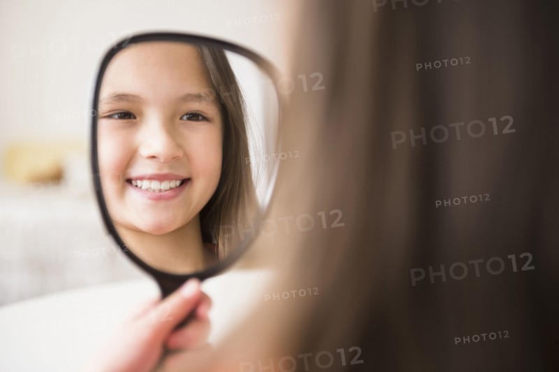 Mixed race girl admiring herself in mirror