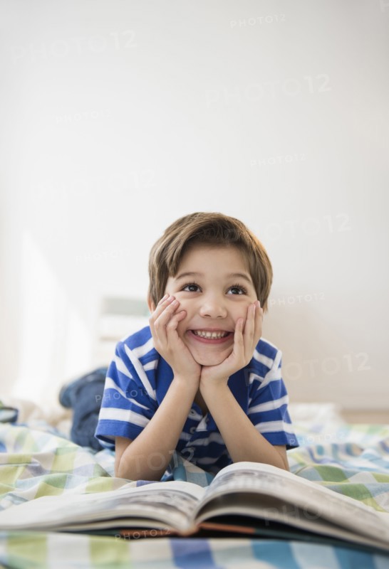 Hispanic boy reading on bed