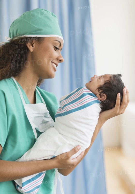 Hispanic doctor holding newborn in hospital