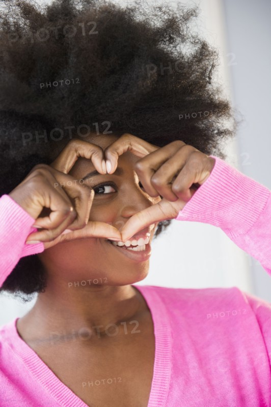 Mixed race woman making heart-shape with fingers