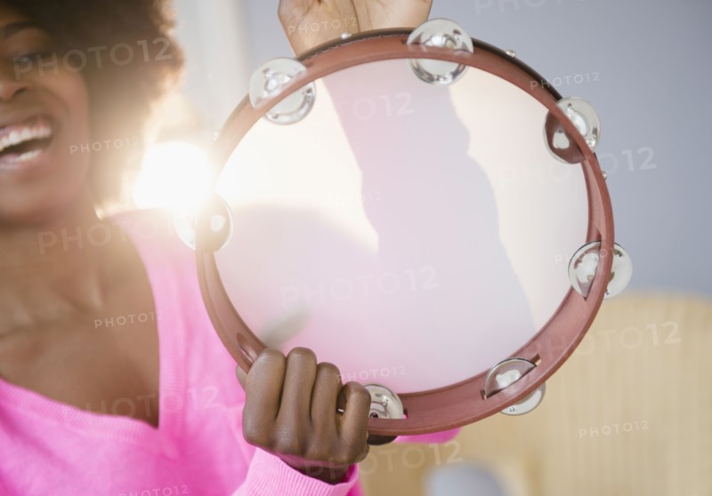 Mixed race woman playing tambourine