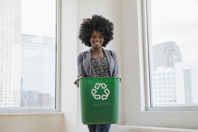 Mixed race businesswoman with recycling bin