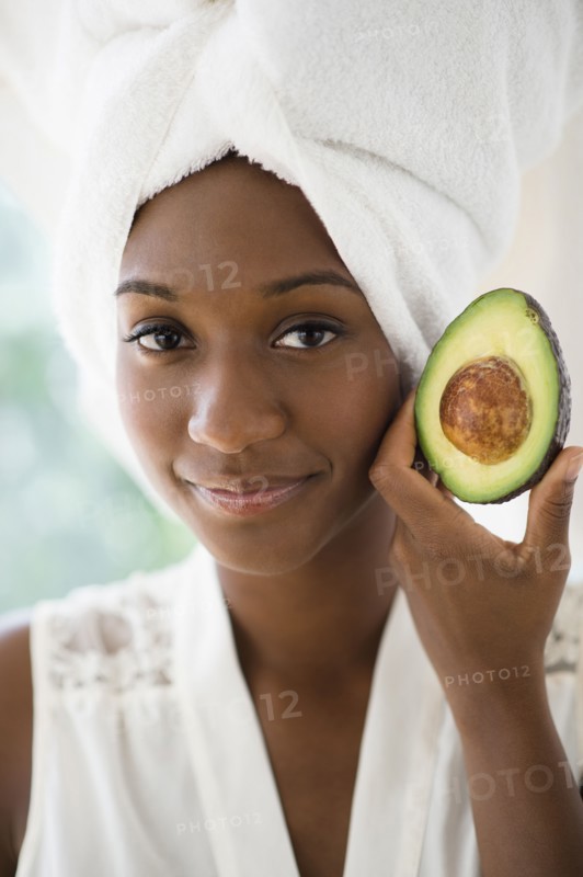 Black woman holding sliced avocado