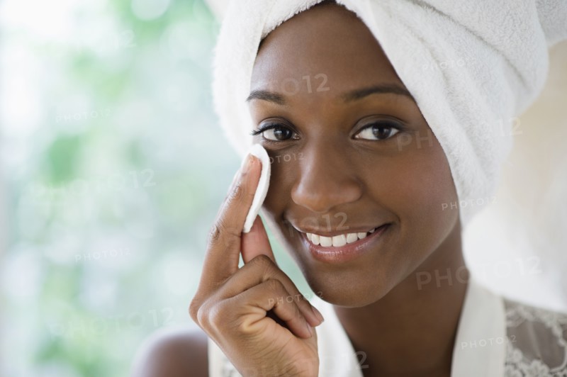 Black woman wiping face with cotton pad